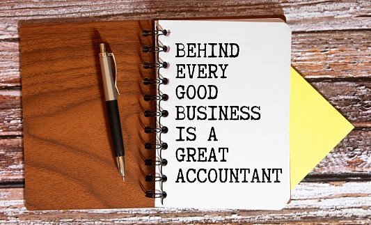 Financial quote Behind Every Good Business Is A Great Accountant handwritten on yellow sticky note on laptop keyboard indicating this is the best CPA firm in Tulsa OK!