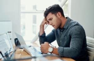 Stress, laptop and business man reading bad news for debt or bankruptcy at creative startup. Main Reasons Businesses File for Bankruptcy - Brown, Chism & Thompson