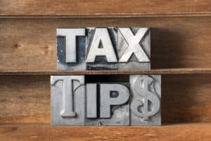 Tax tips phrase made from metallic letterpress type on wooden tray. 7 Tax Tips for Freelancers - Brown, Chism & Thompson.